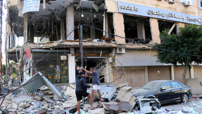 People inspect the damage of one Al-Qard Al-Hassan branch in the southern port city of Tyre after it was hit by Israel [Getty]