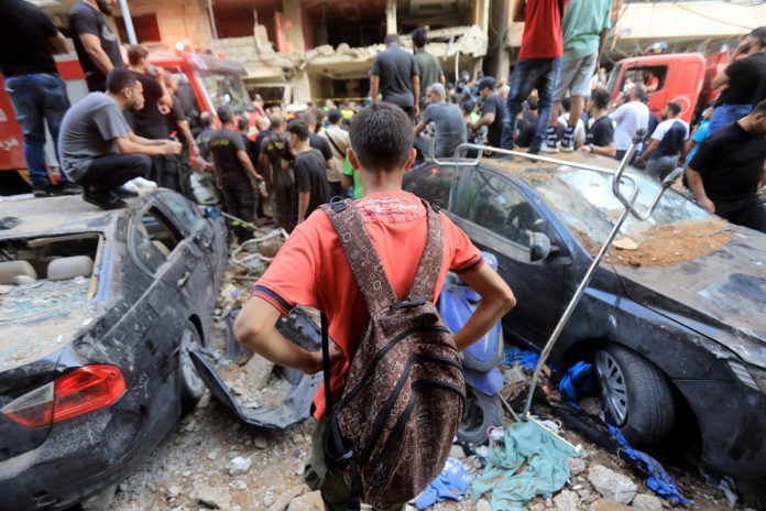 Child watching people trying to remove rubbles from a destructed site in Beirut southern suburbs